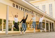 Springende Studentinnen vor Unieingang