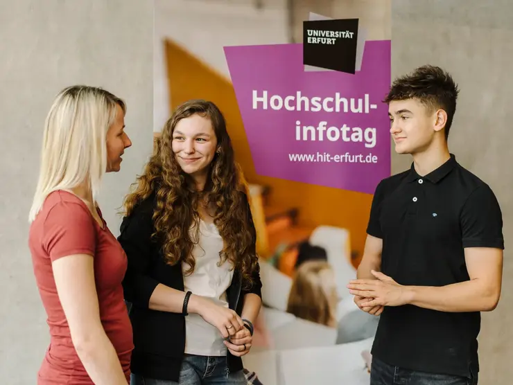 Drei Studierende vor Werbebanner für Hochschulinfotag