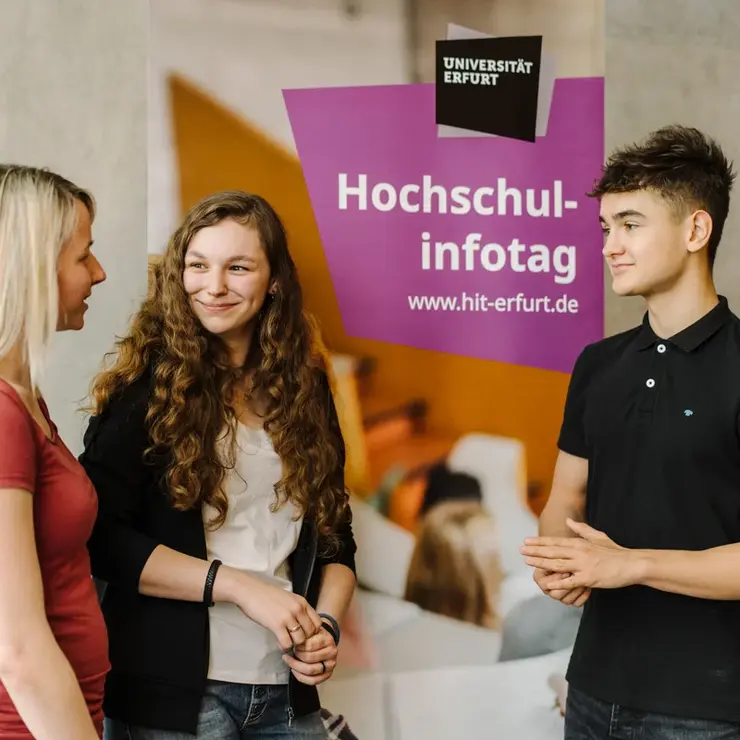 Drei Studierende vor Werbebanner für Hochschulinfotag