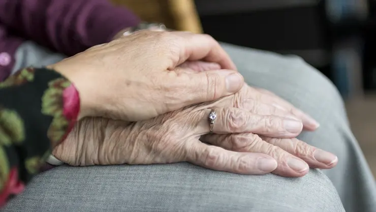 Eine junge Frau legt ihr Hand auf die einer älteren