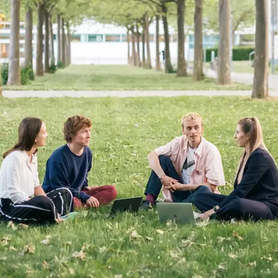 Junge Menschen sitzen auf einer Wiese