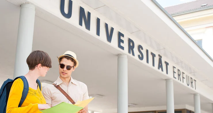 Studierende stehen vor dem Haupteingang zur Universität Erfurt