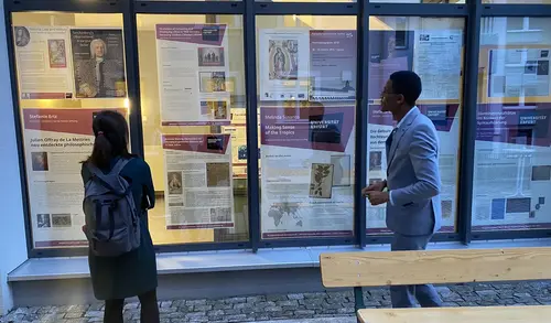 Zwei Fellows des Herzog-Ernst-Stipendienprogramms betrachten die Posterausstellung mit einer Auswahl von Projekten und Veranstaltungen aus 20 Jahre FZG