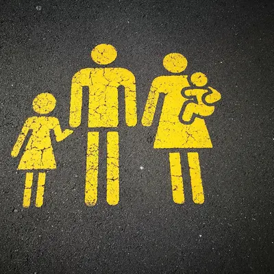 Bright yello graffito on tarmac, showing icons of a man, woman and two small children